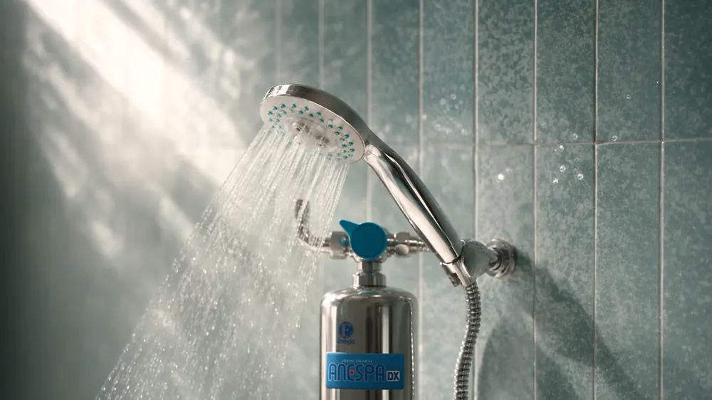 Water running from the ANESPA DX handheld shower head against sage tile